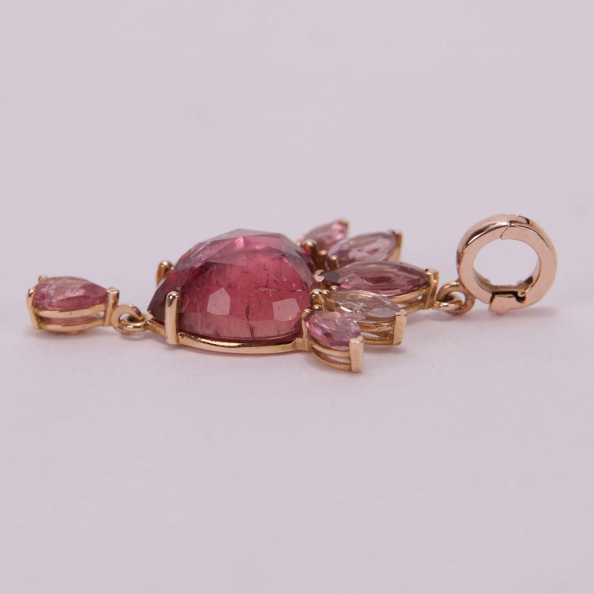 Gold pendant with pink gemstones on display.