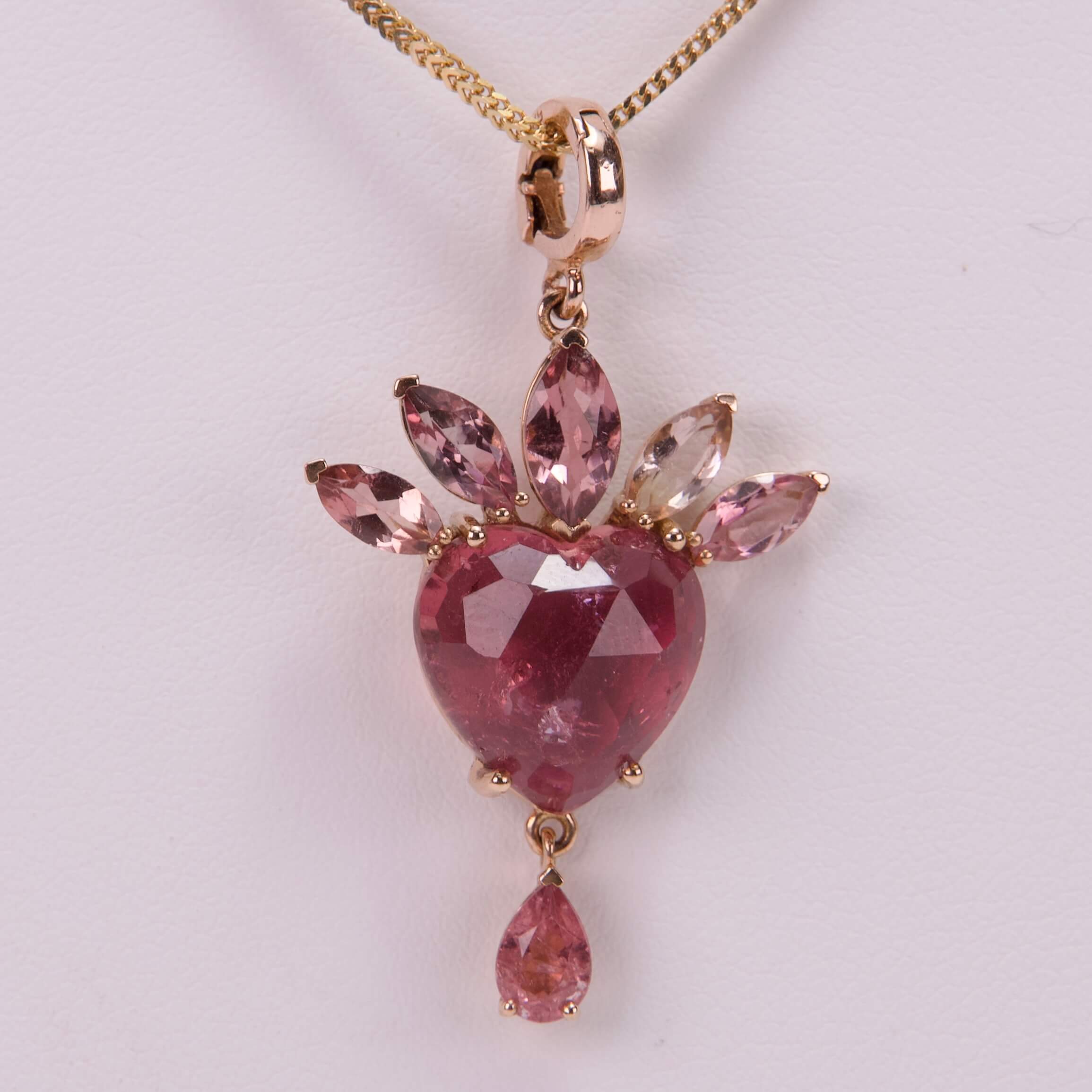 Pink gemstone heart pendant with gold chain.