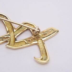 Gold brooch with intricate design and markings.