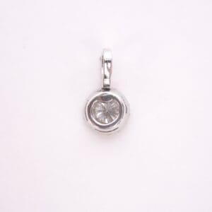 Silver round pendant with clear gemstone.