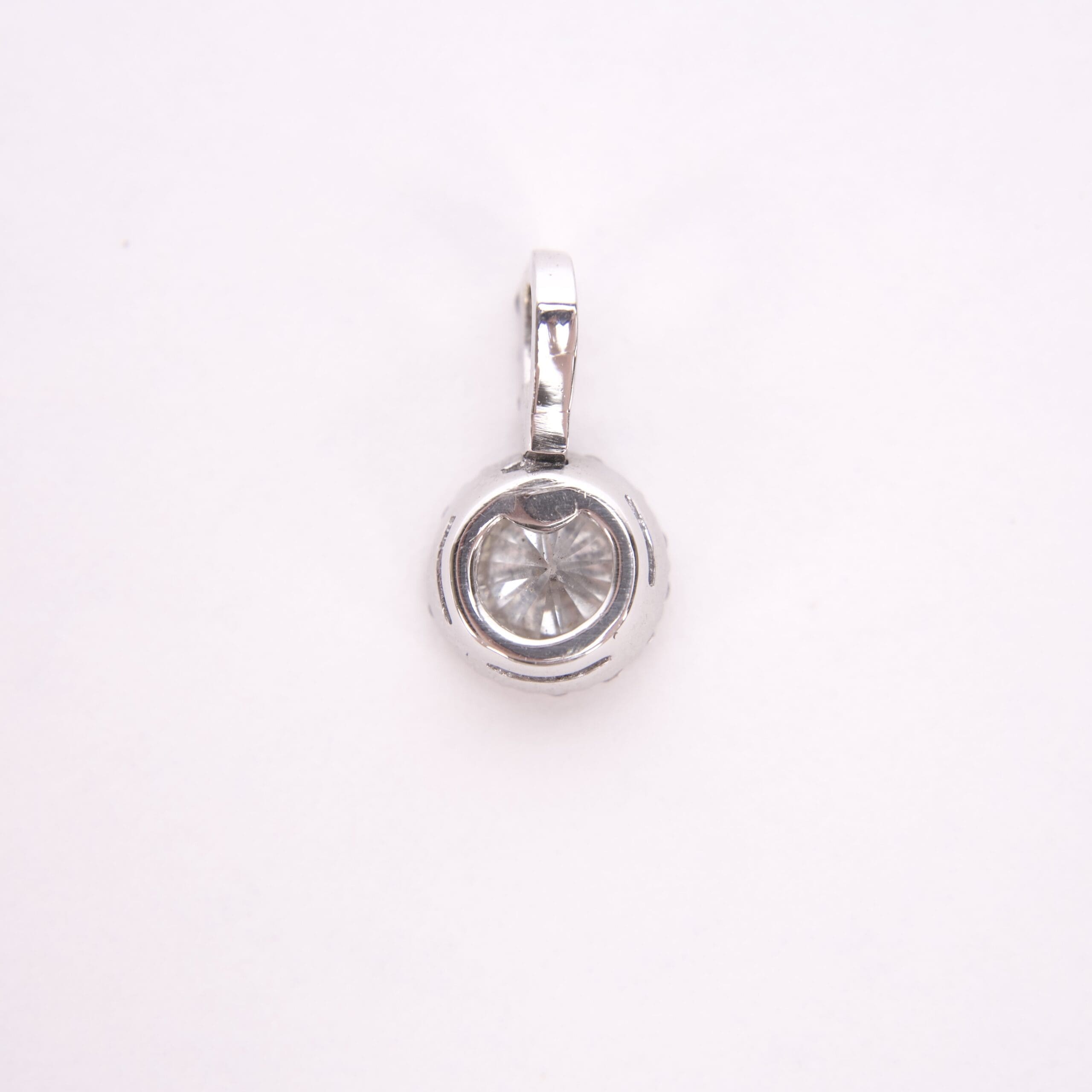 Silver round pendant with clear gemstone.