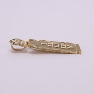Gold pendant with engraved text design.