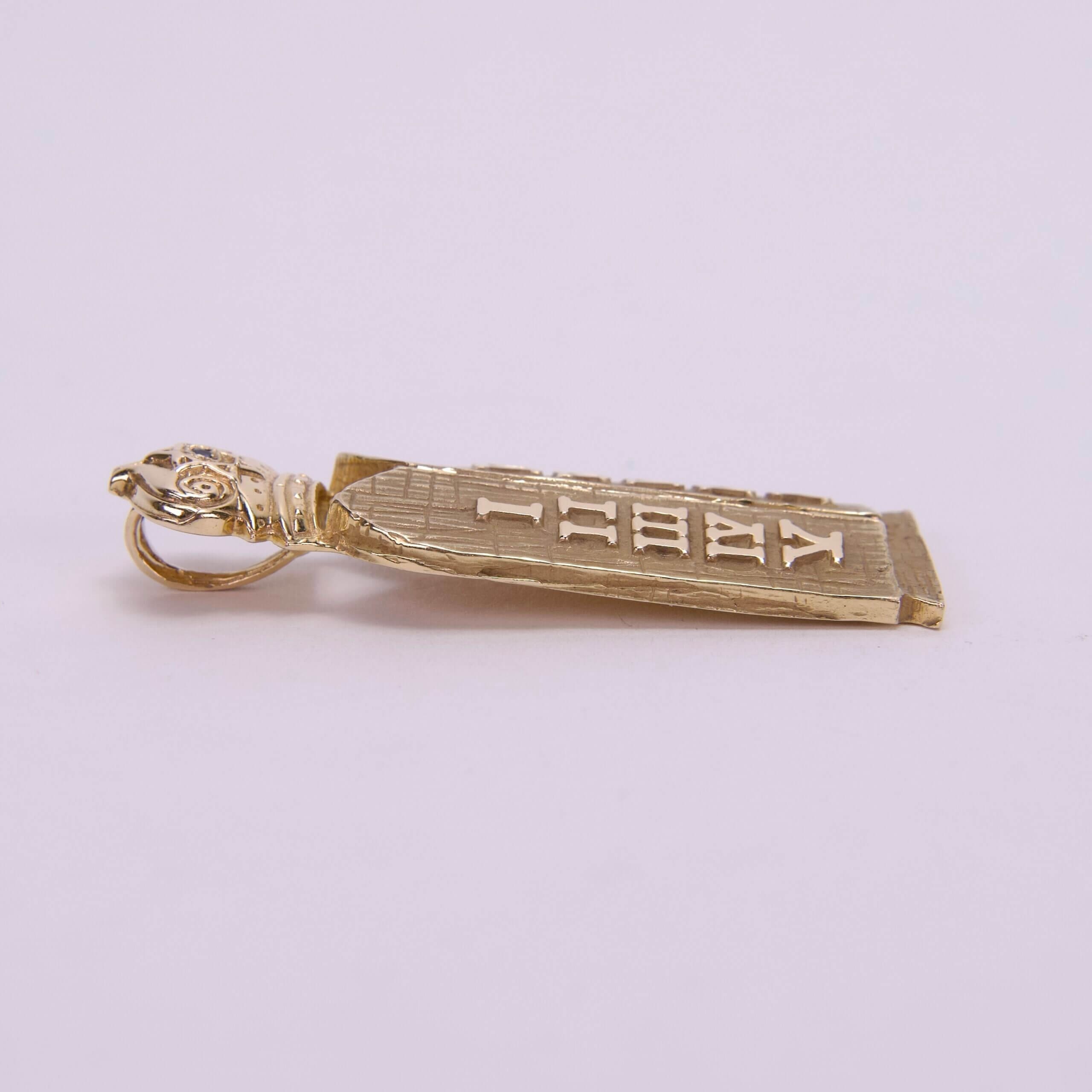 Gold pendant with engraved text design.