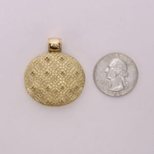 Gold locket beside a US quarter coin.