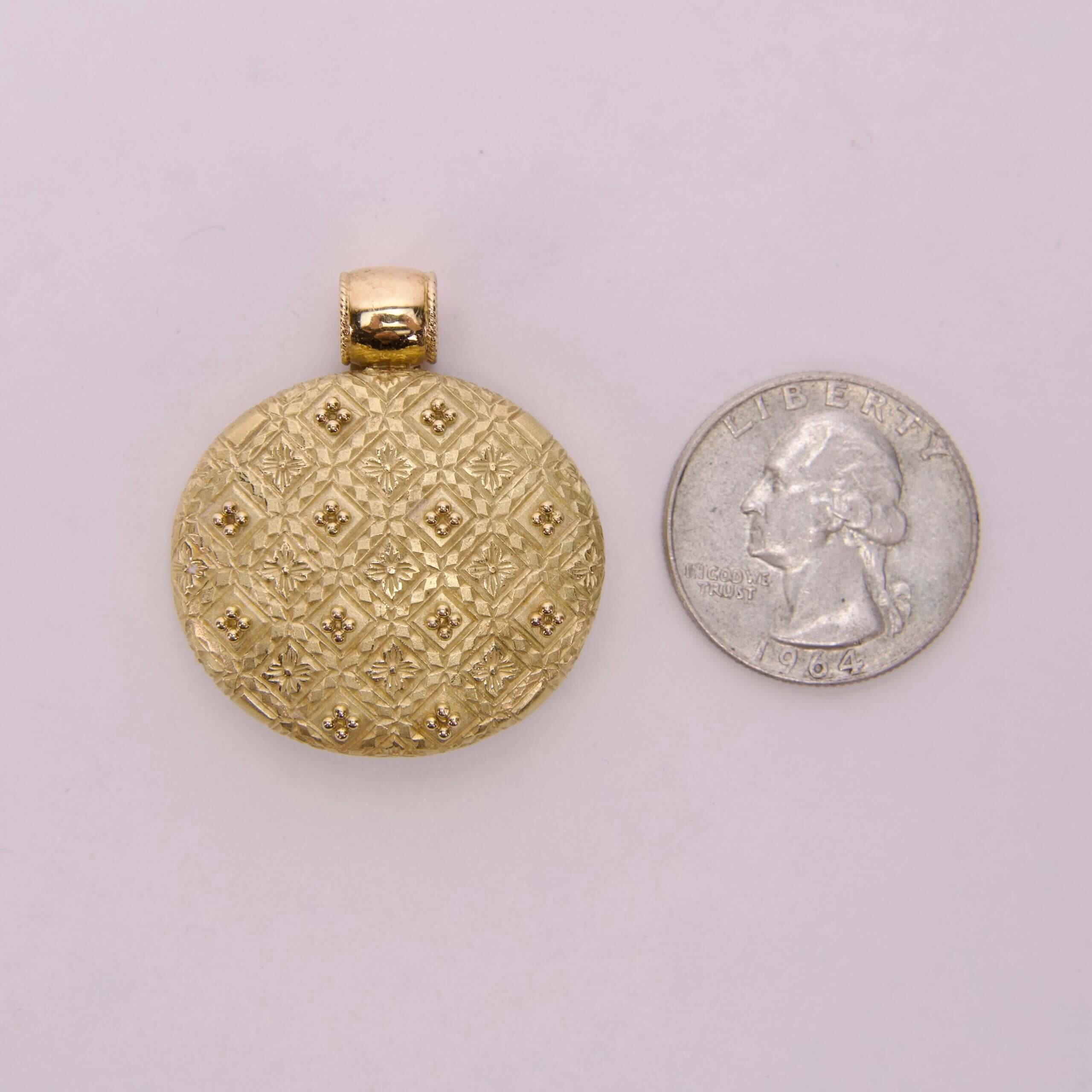 Gold locket beside a US quarter coin.