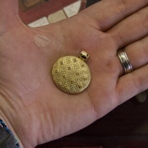 Gold pendant in a person's hand.