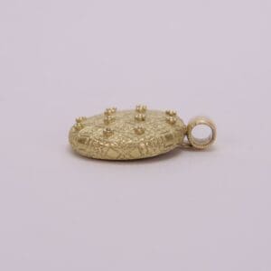 Gold pendant with engraved pattern and studs.