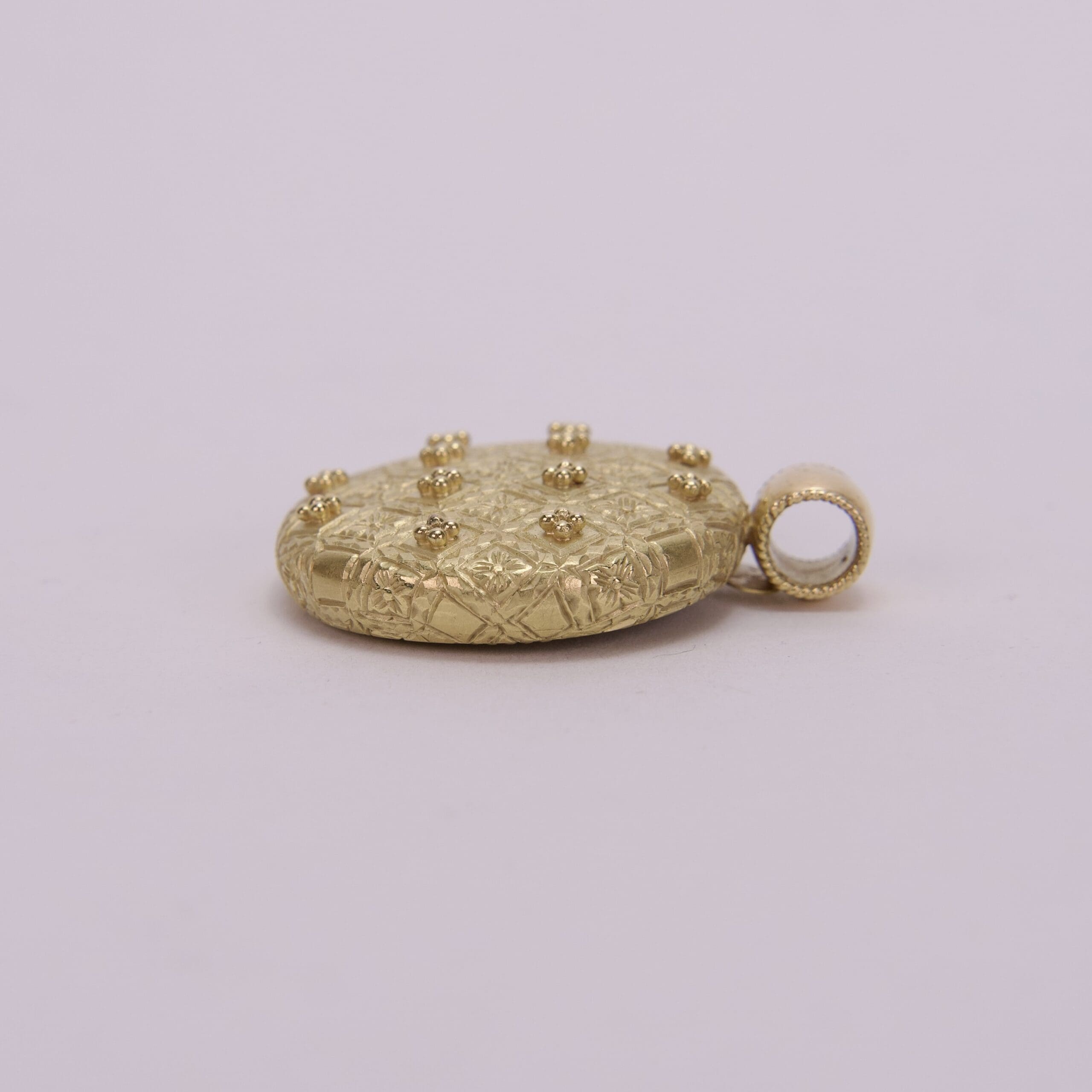 Gold pendant with engraved pattern and studs.