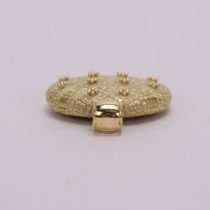 Gold decorative object with intricate patterns.