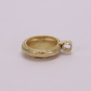 Gold pendant with intricate engraved design.