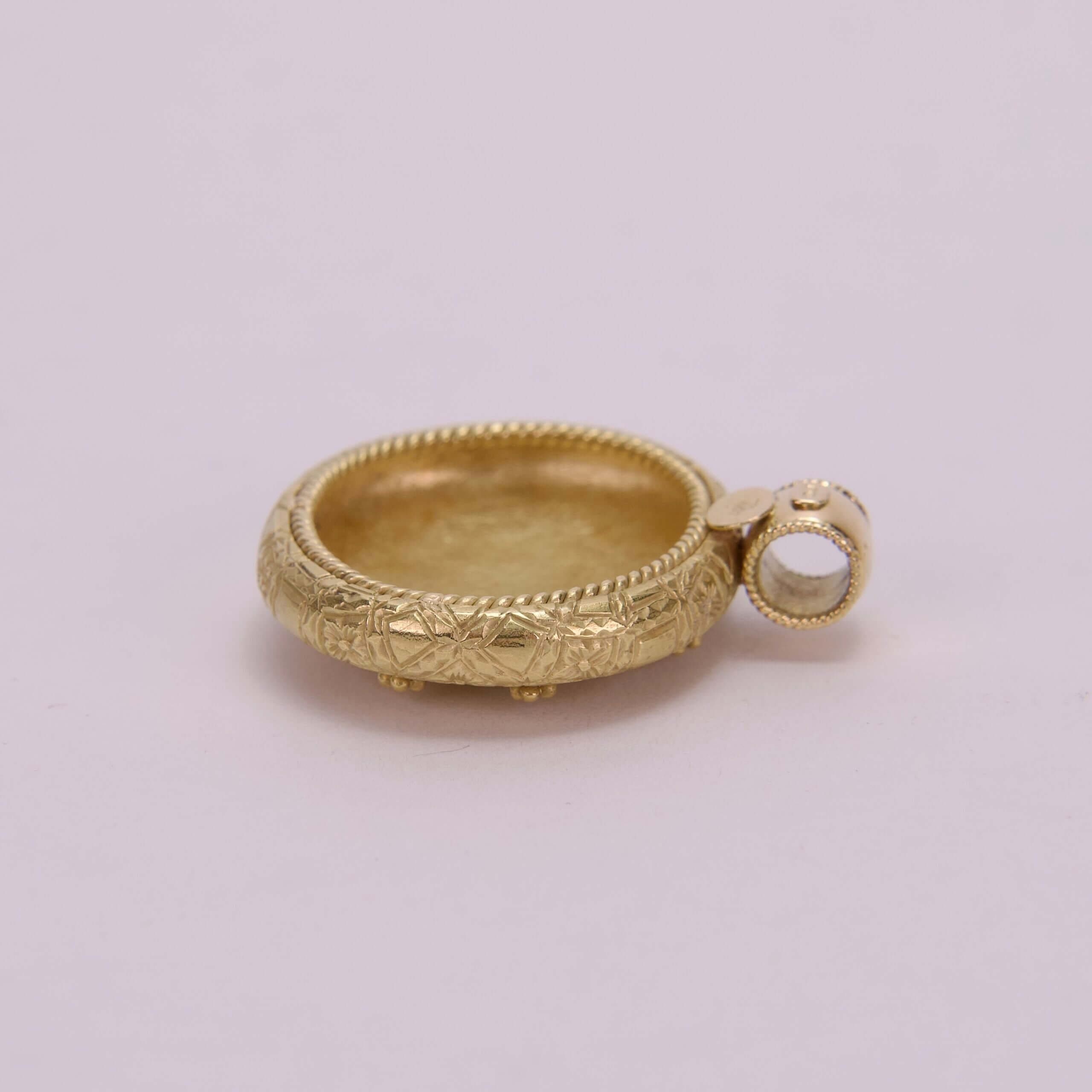 Gold pendant with intricate engraved design.
