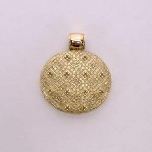 Gold circular pendant with textured pattern.