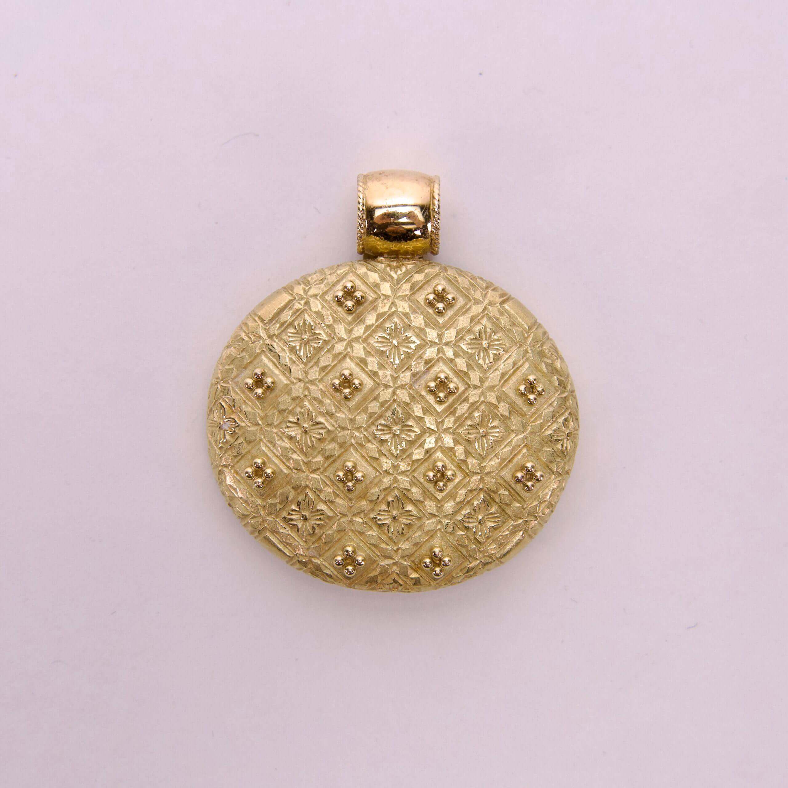 Gold circular pendant with textured pattern.