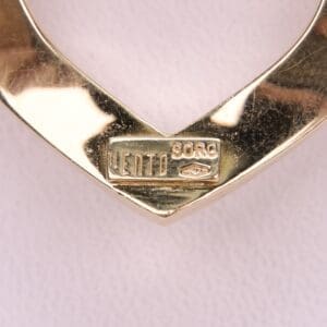 Gold heart-shaped pendant with engraved text.