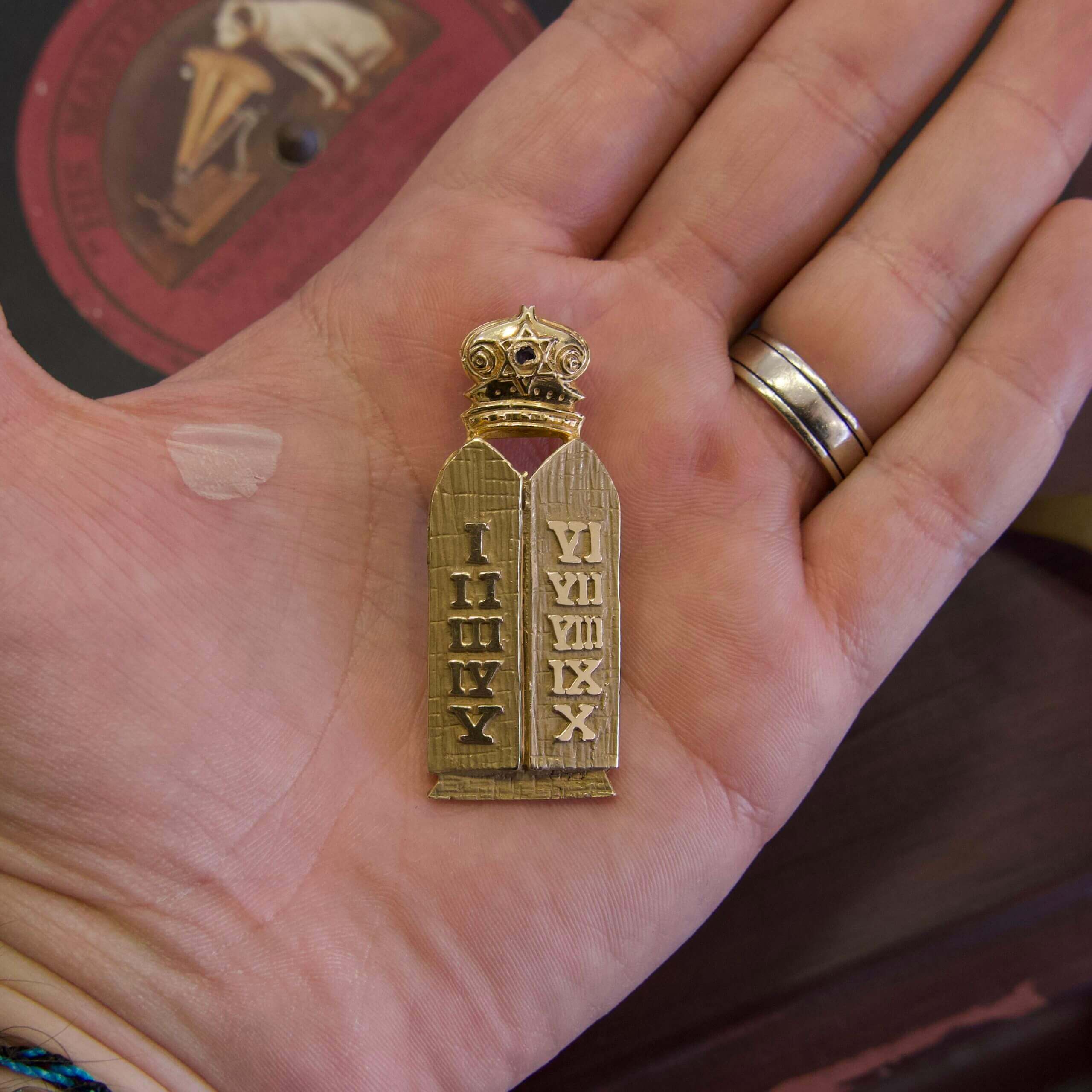 Hand holding small decorative Ten Commandments tablet.