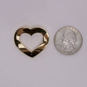 Gold heart cutout beside a quarter coin.