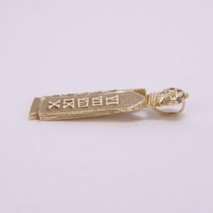 Gold pendant with engraved symbols, side view.