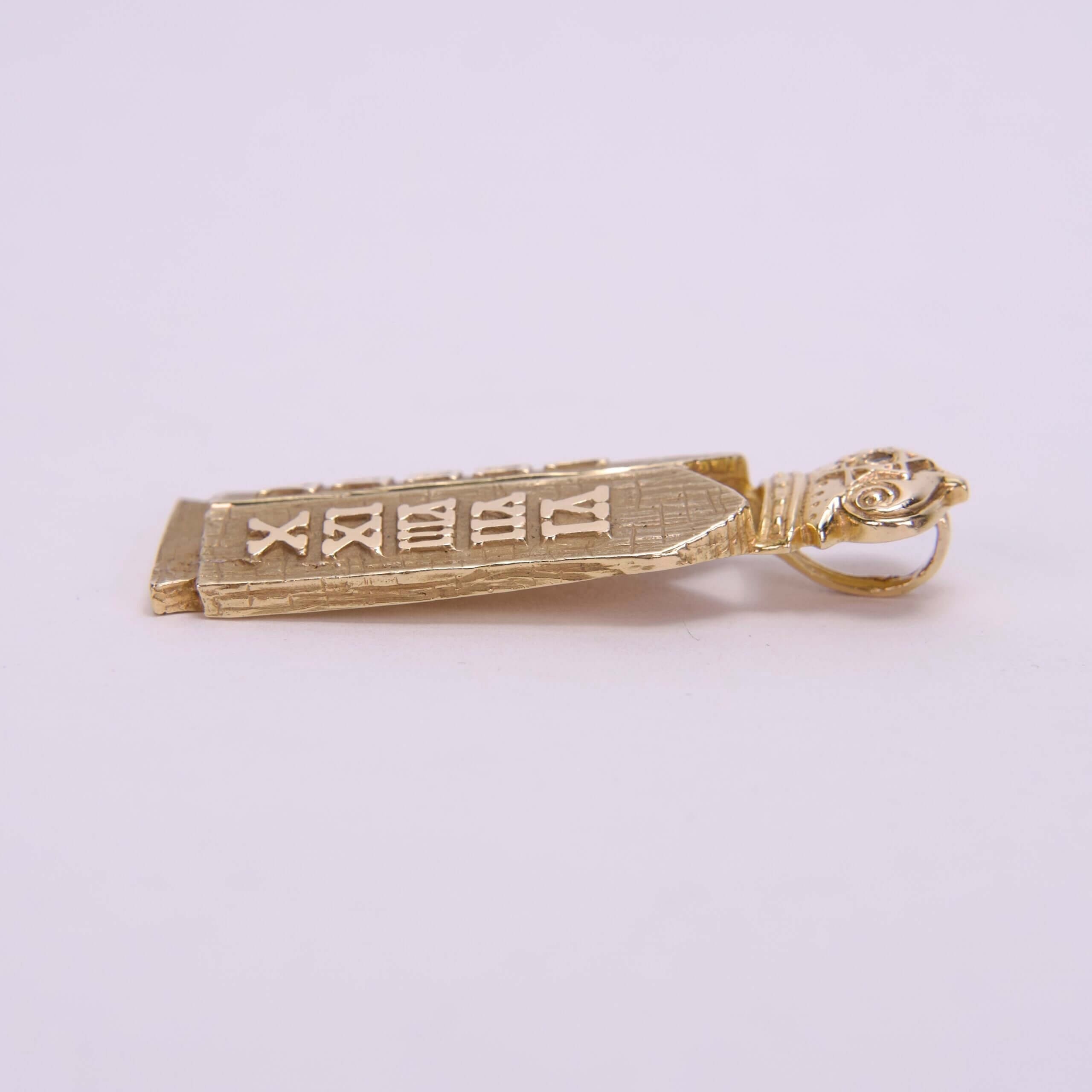 Gold pendant with engraved symbols, side view.