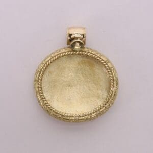 Gold pendant with intricate border design.