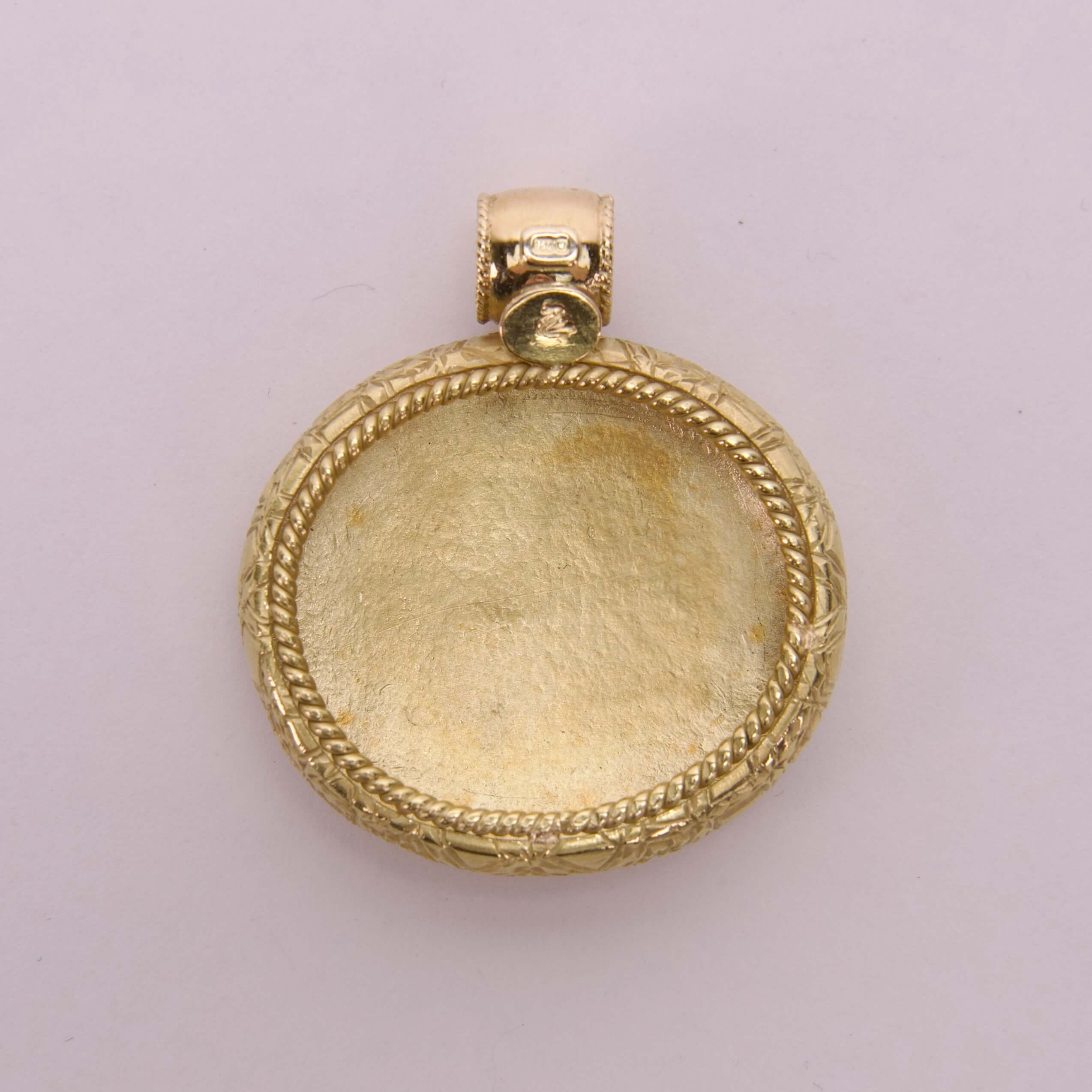 Gold pendant with intricate border design.