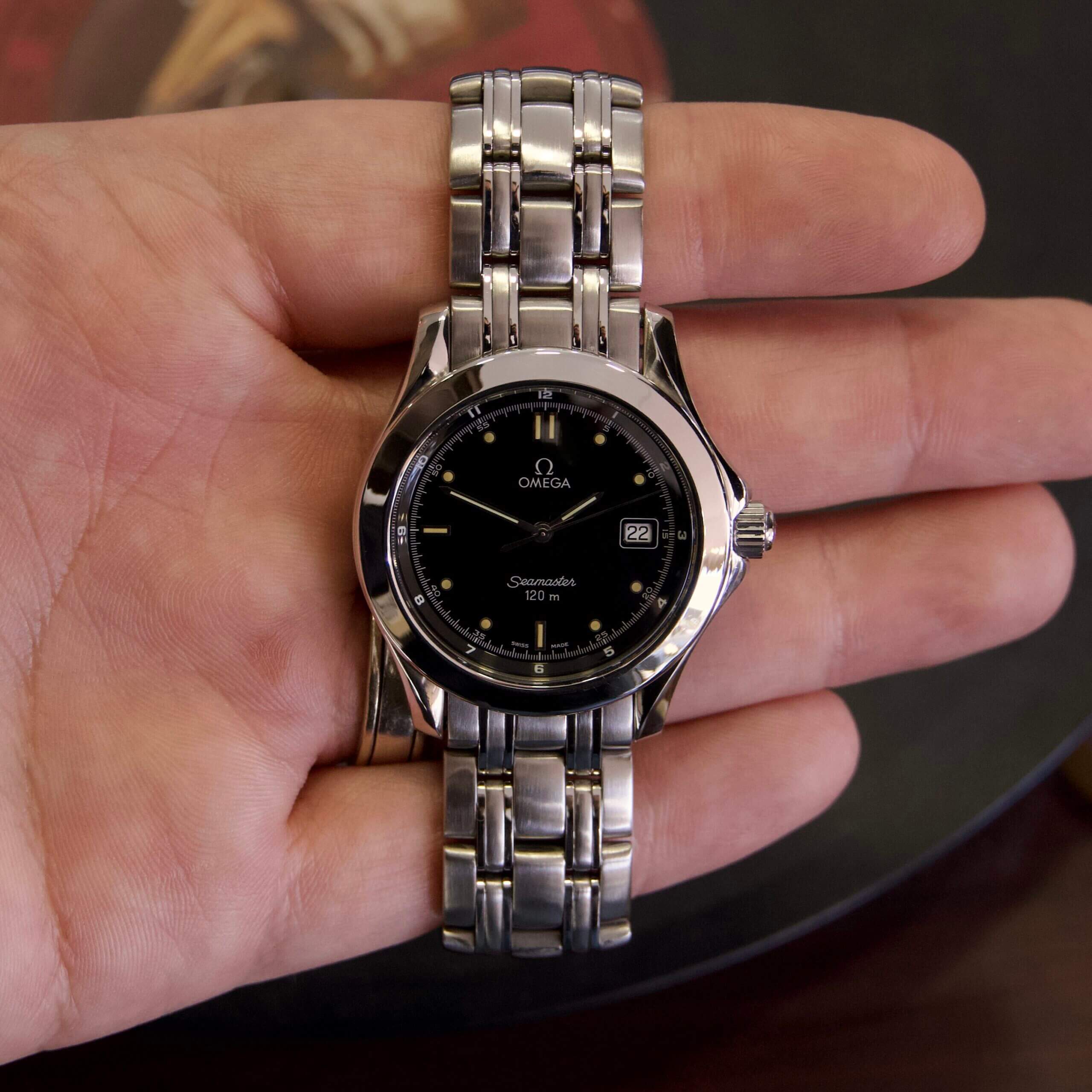 Hand holding a silver wristwatch.