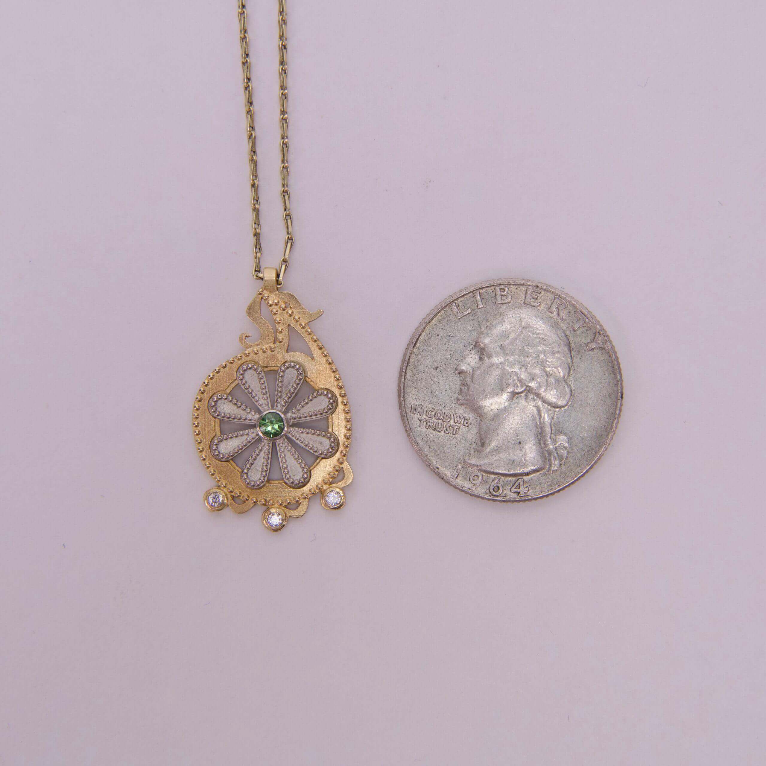 Necklace pendant beside a US quarter coin.