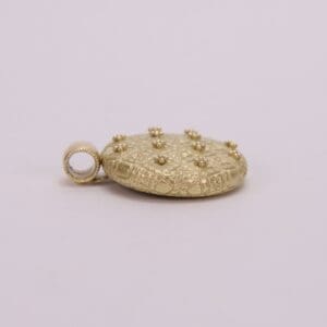 Gold textured pendant with loop attachment.