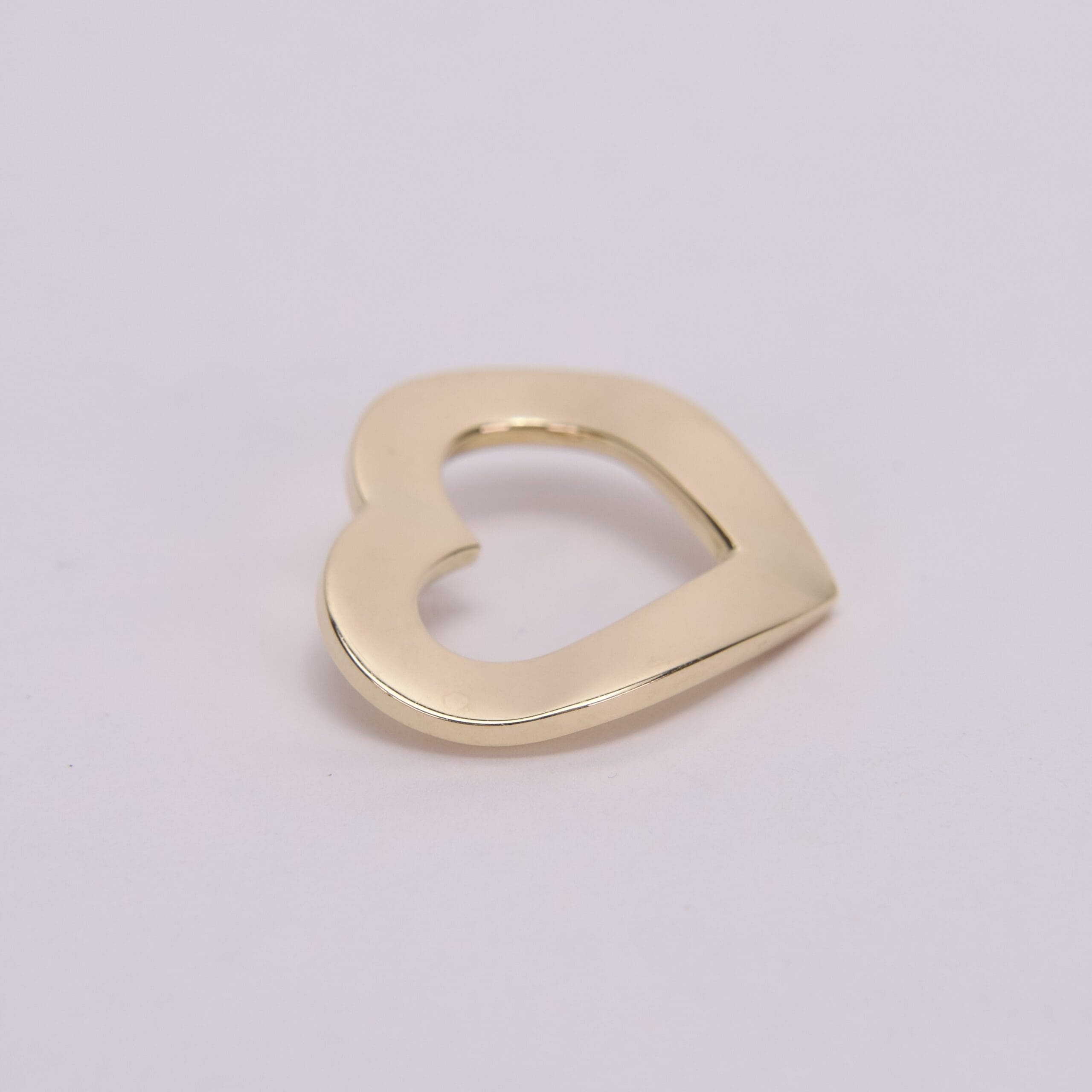 Gold heart-shaped pendant on light background.