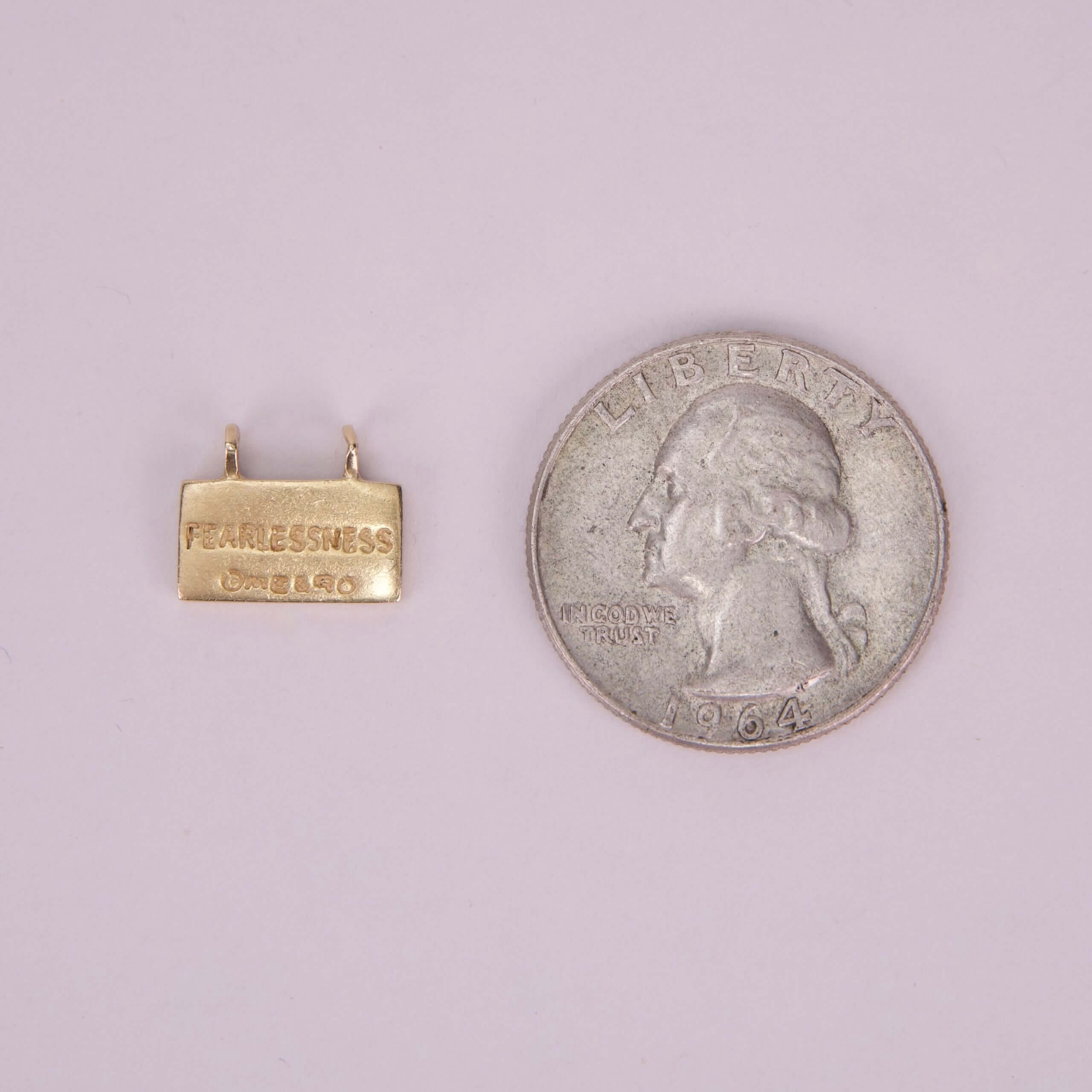 Gold charm next to a 1964 quarter.