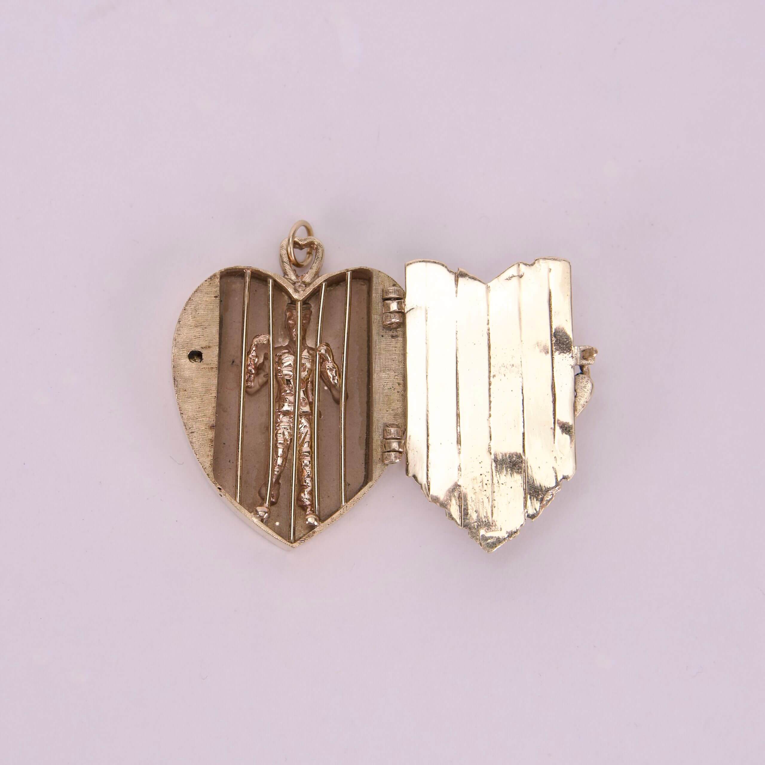 Heart-shaped locket with small figure inside.