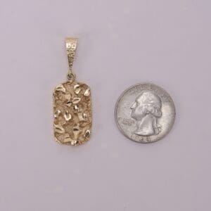 Gold pendant next to a quarter.