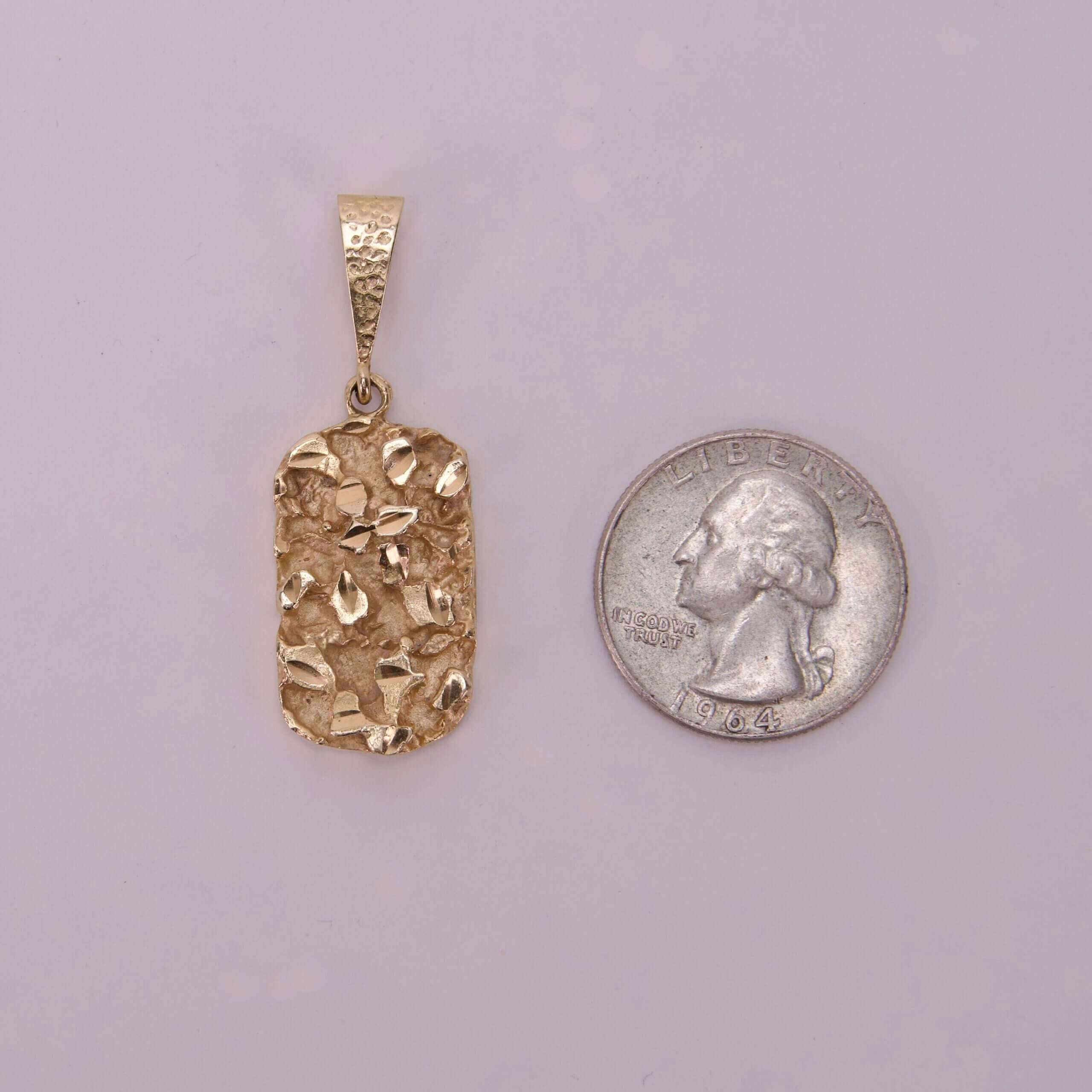 Gold pendant next to a quarter.