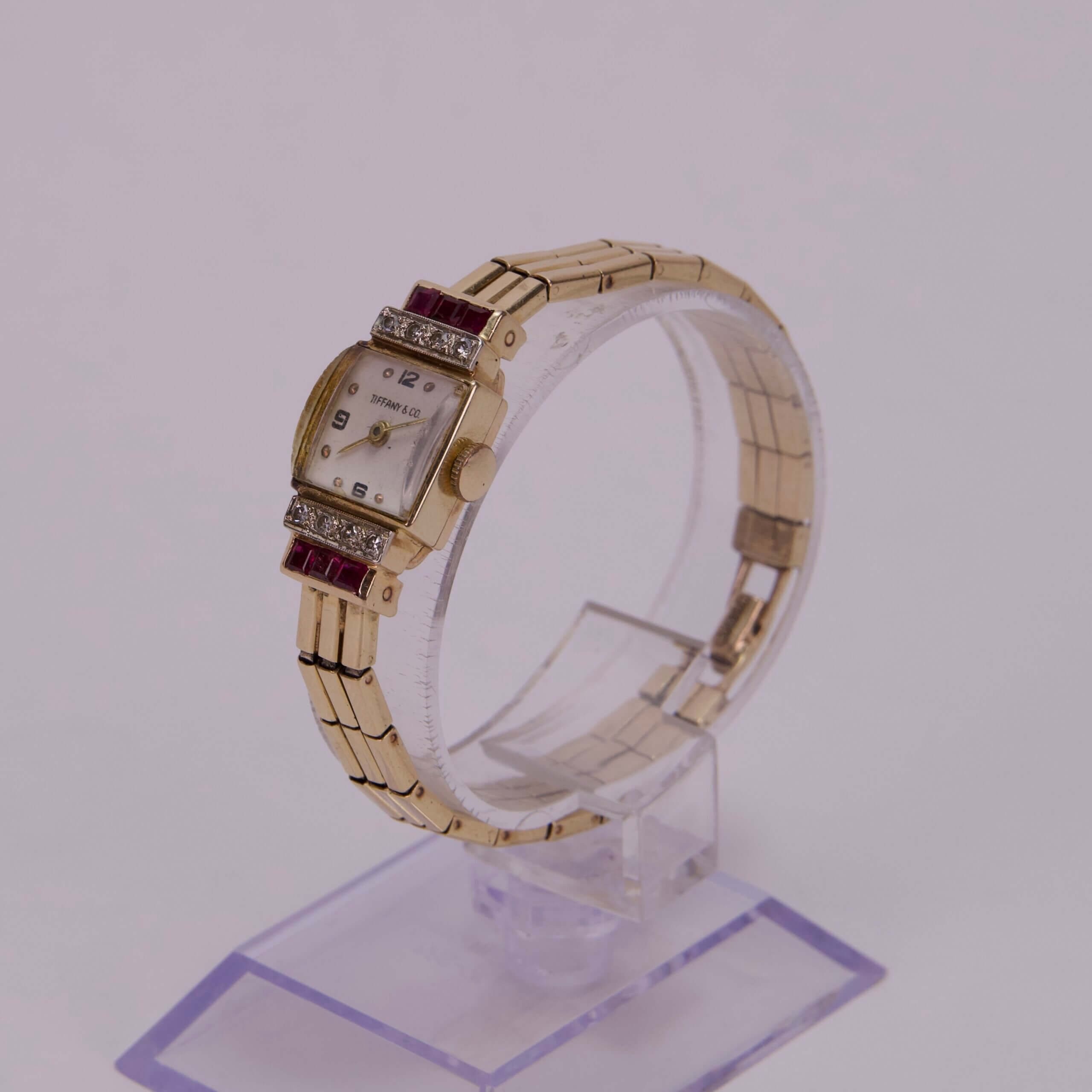 Gold watch with gemstones on stand.