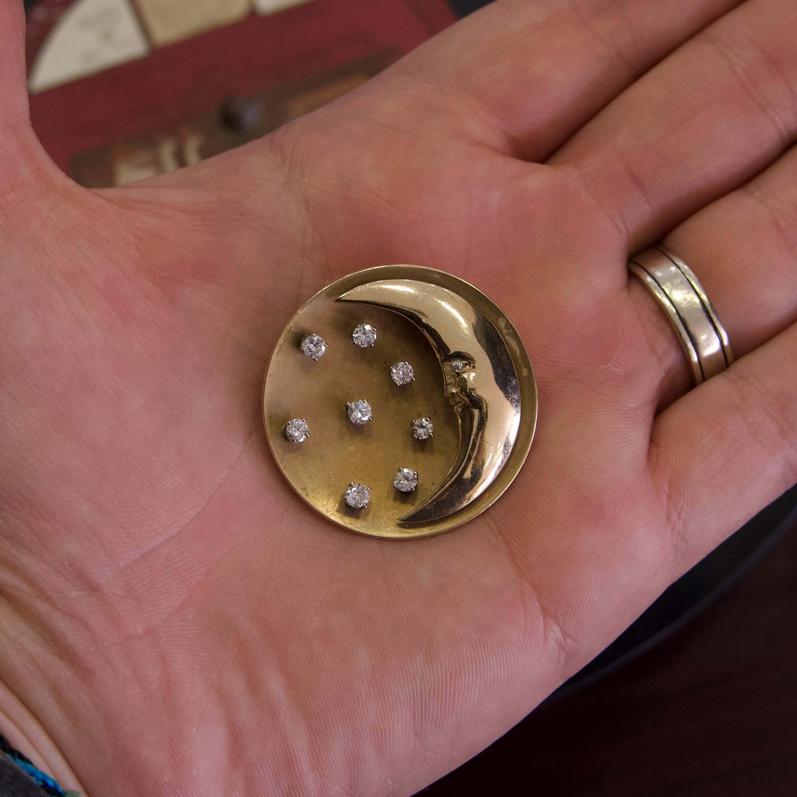 Hand holding a moon and stars badge.