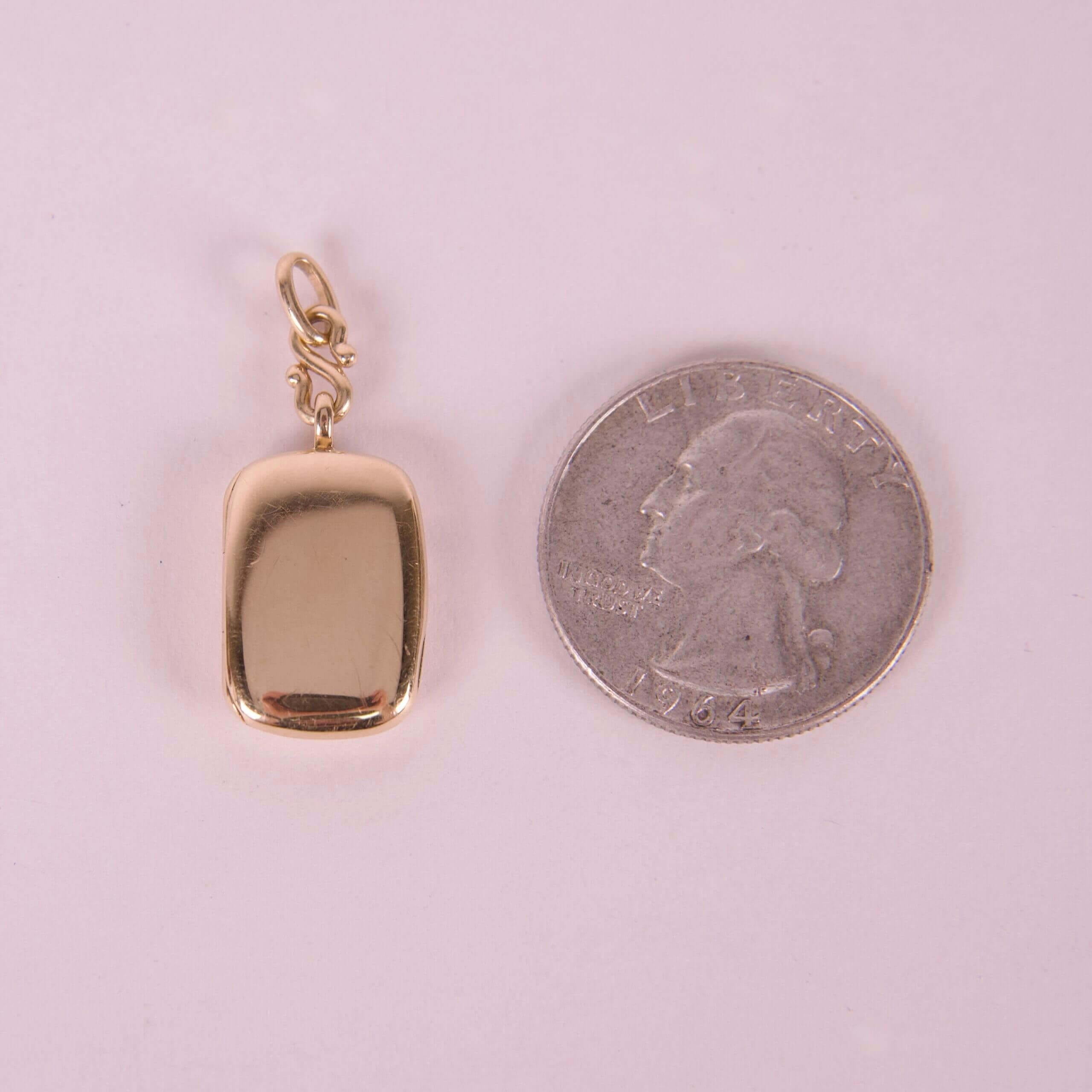 Gold pendant beside a U.S. quarter.