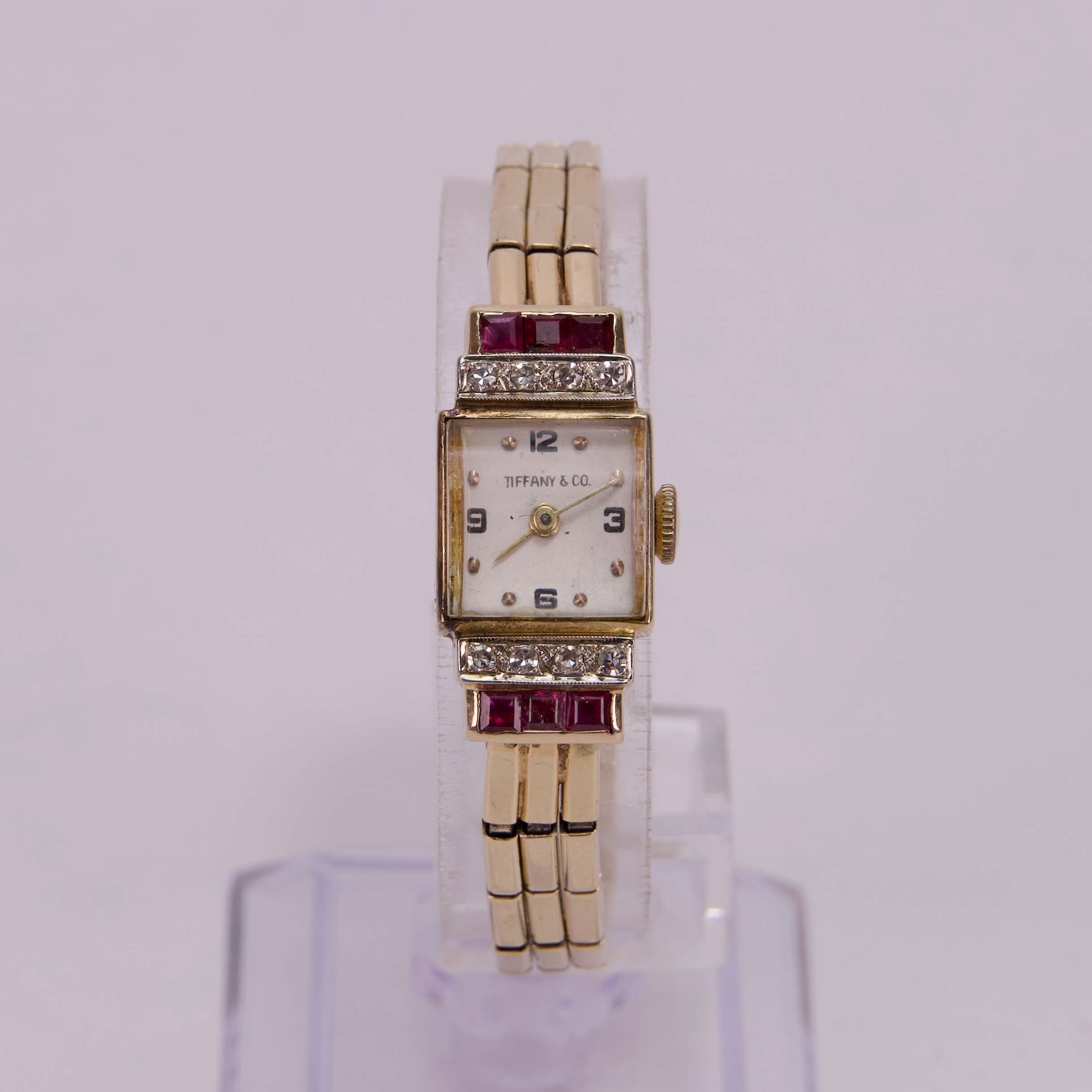 Gold wristwatch with red accents.
