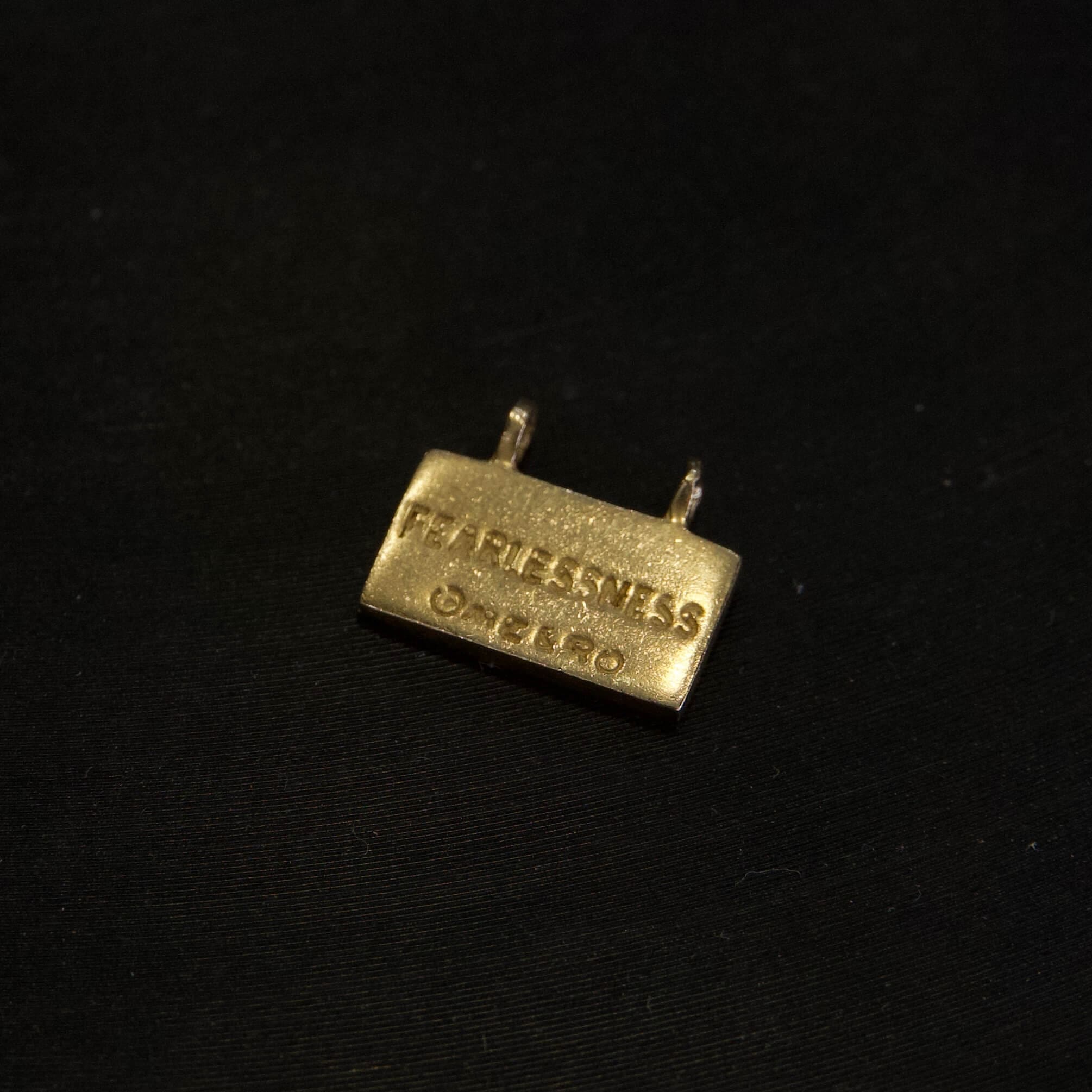 Gold pin labeled "Fearlessness" on black background.