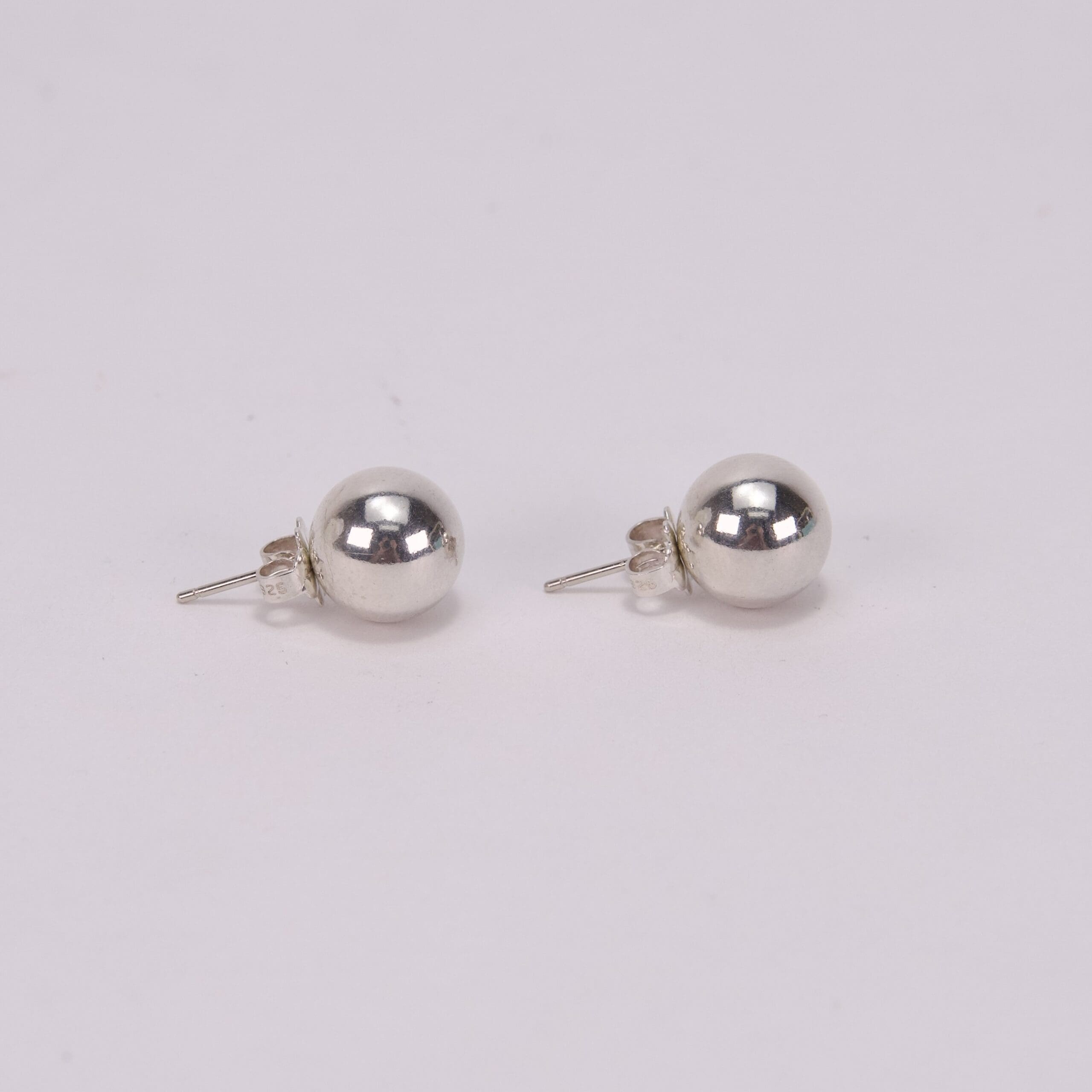 Silver ball stud earrings on white background.