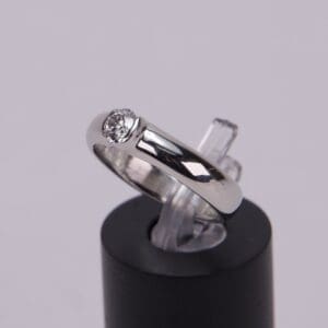 Silver ring with diamond on display stand.