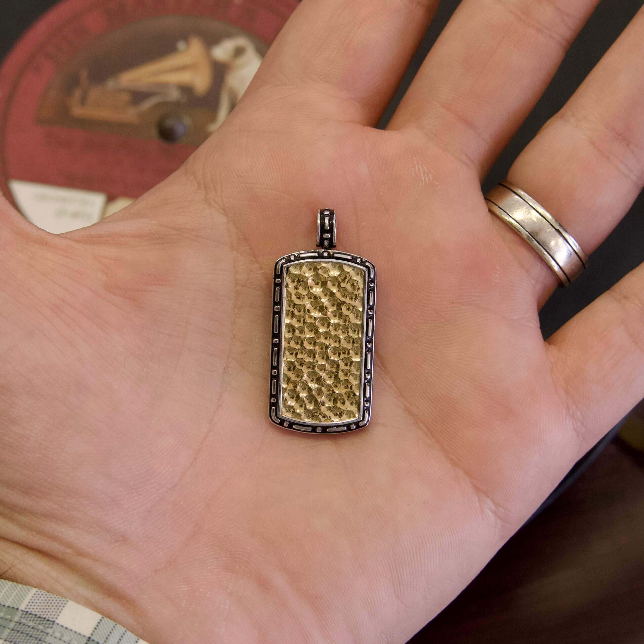Gold rectangular pendant on open hand.