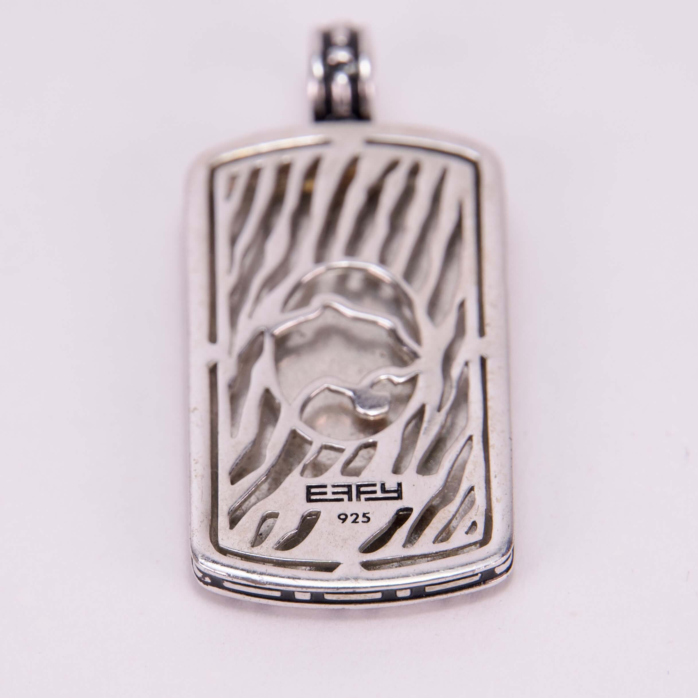 Silver pendant with abstract design and engraving.