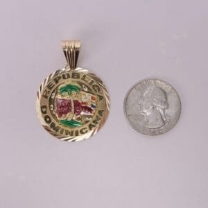 Gold Dominican Republic pendant beside quarter.