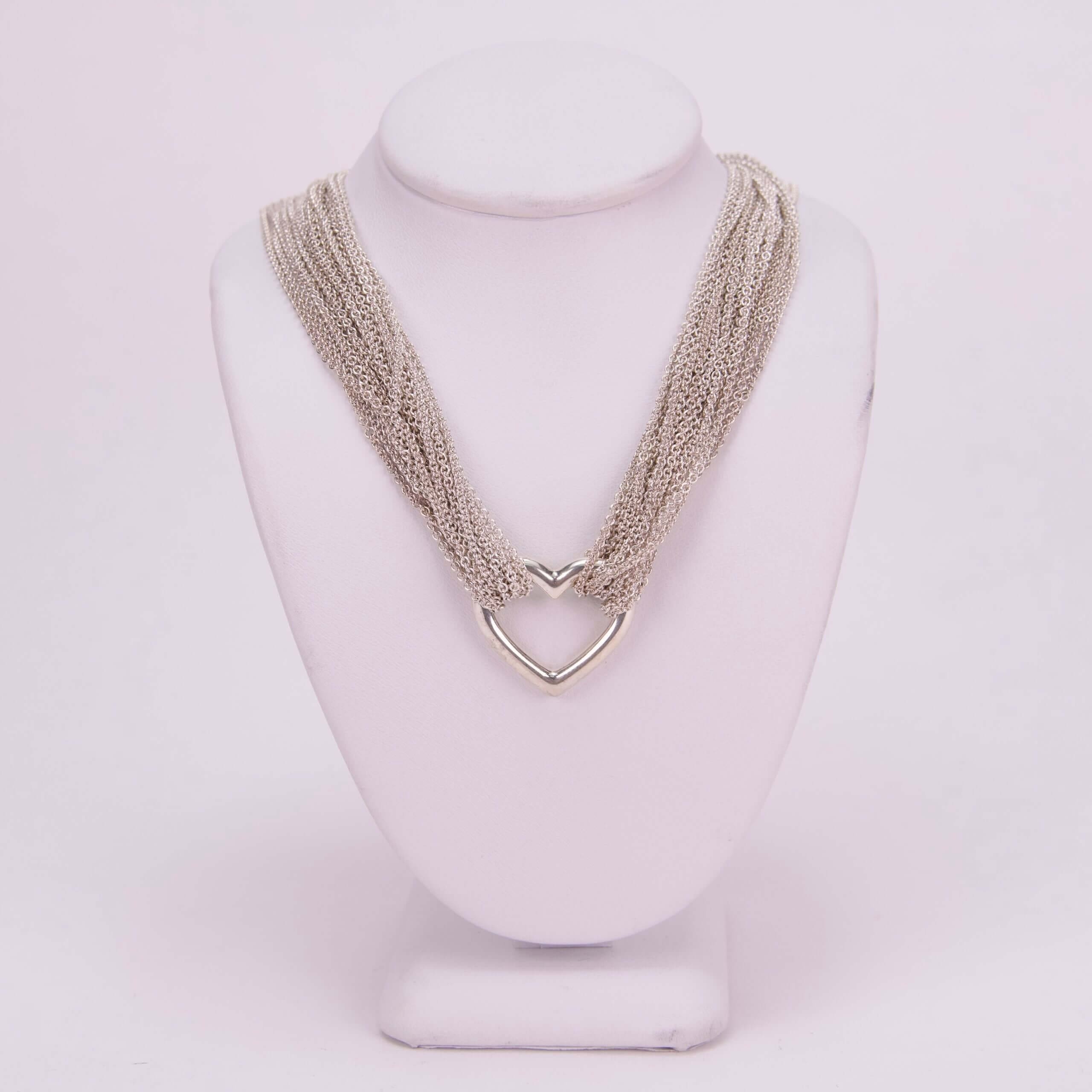 Silver necklace on white display stand.