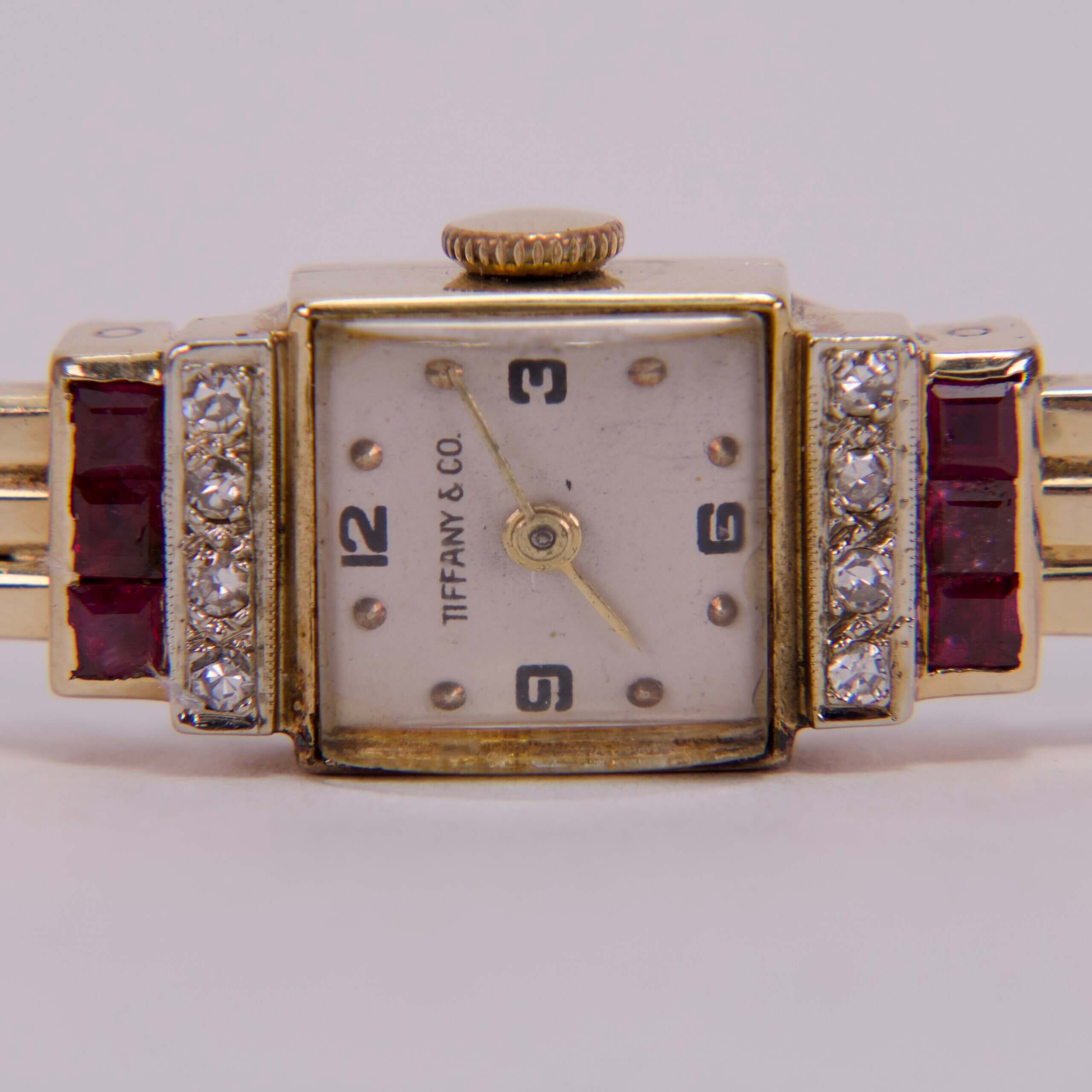 Gold watch with diamonds and red gems.