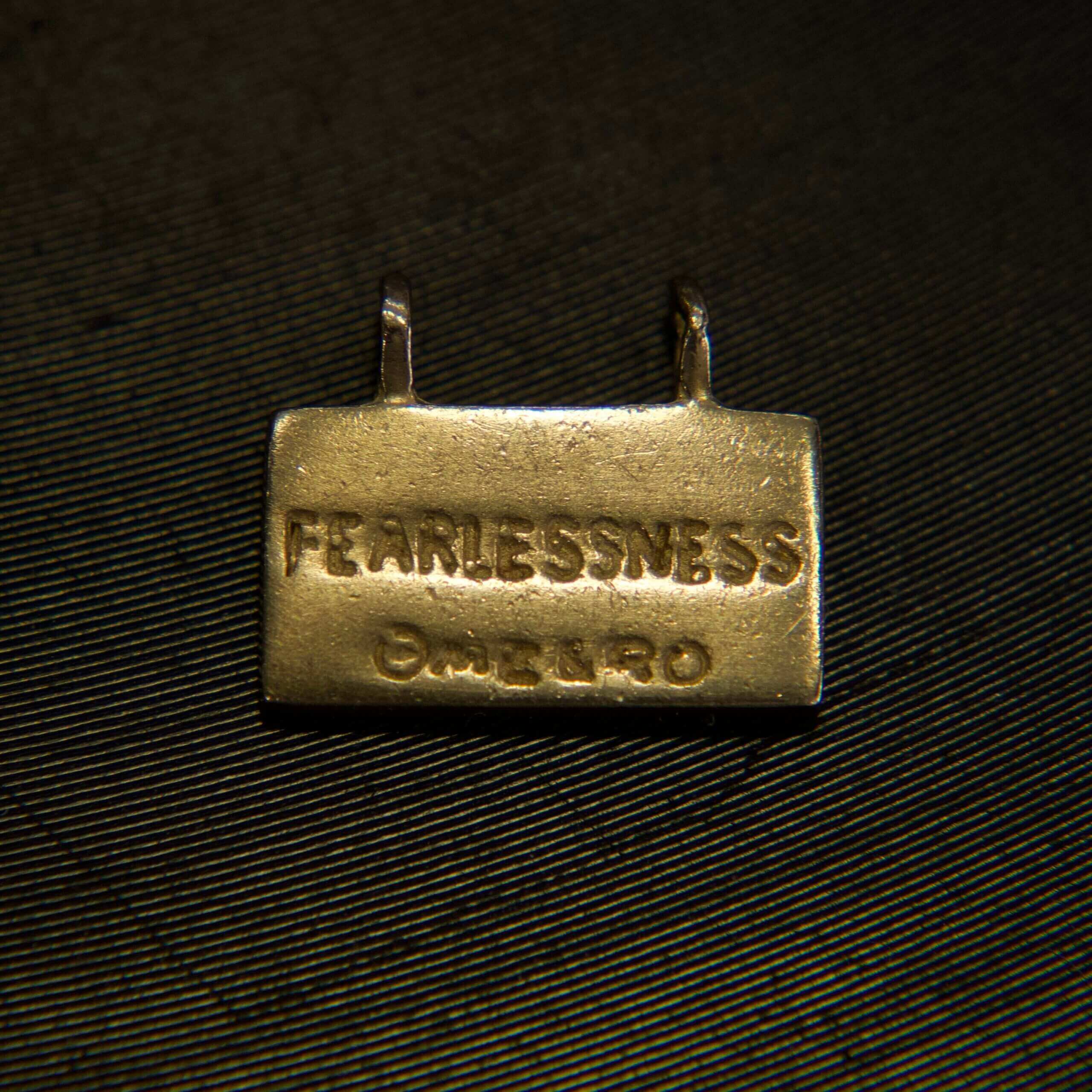 Metal tag with "FEARLESSNESS" engraving.