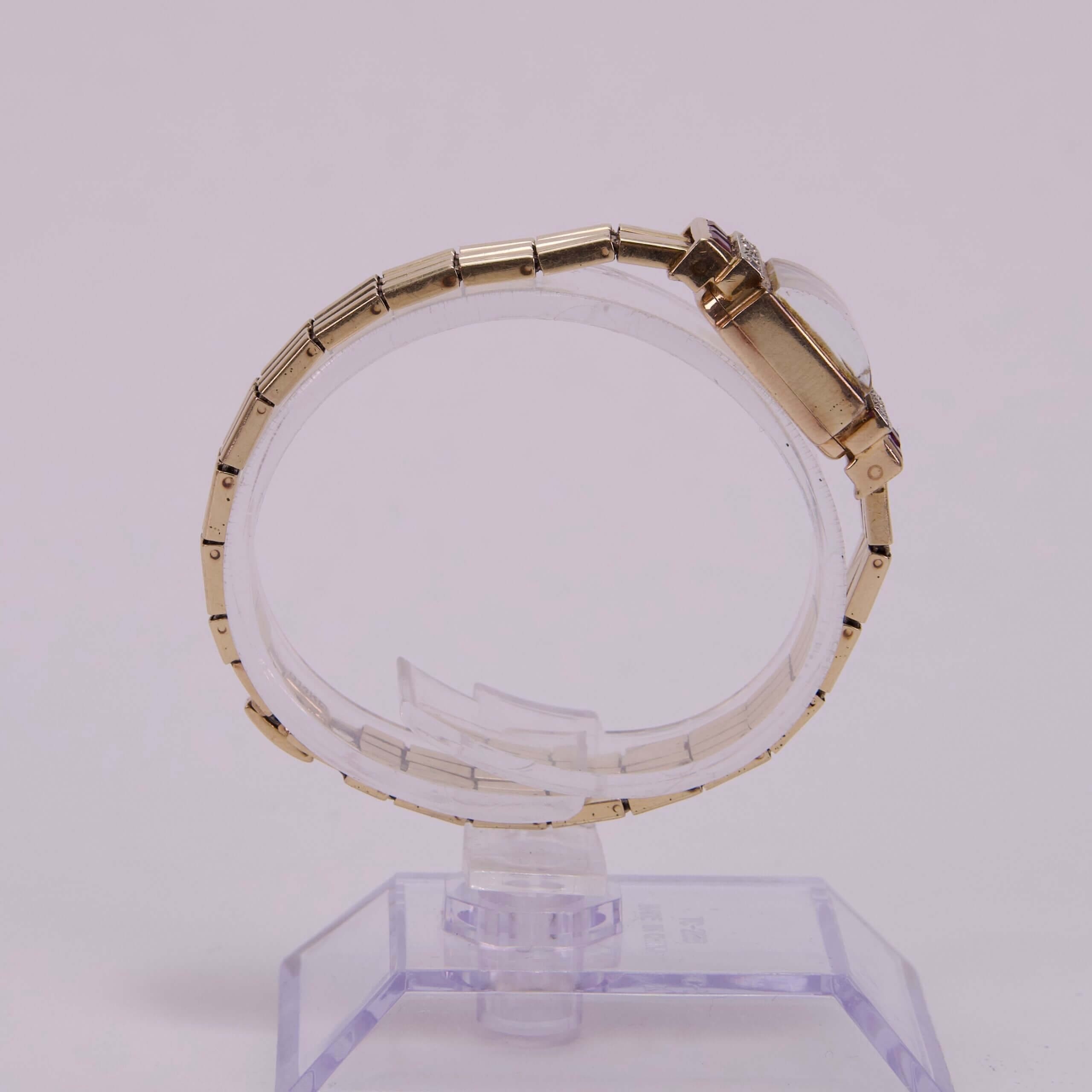 Gold wristwatch displayed on clear stand.