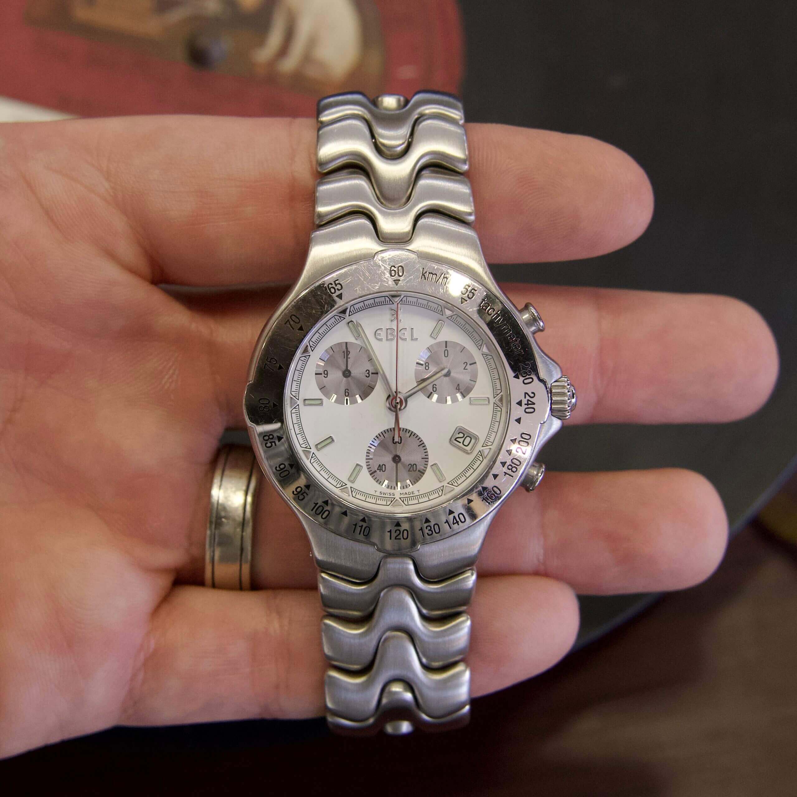 Hand holding a silver wristwatch with chronograph.