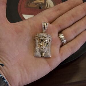 Hand holding a jeweled pendant of Jesus.