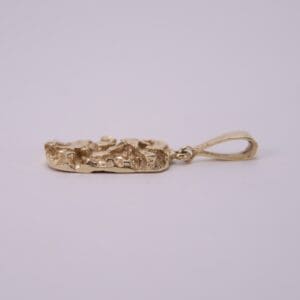 Gold pendant with textured design, side view.