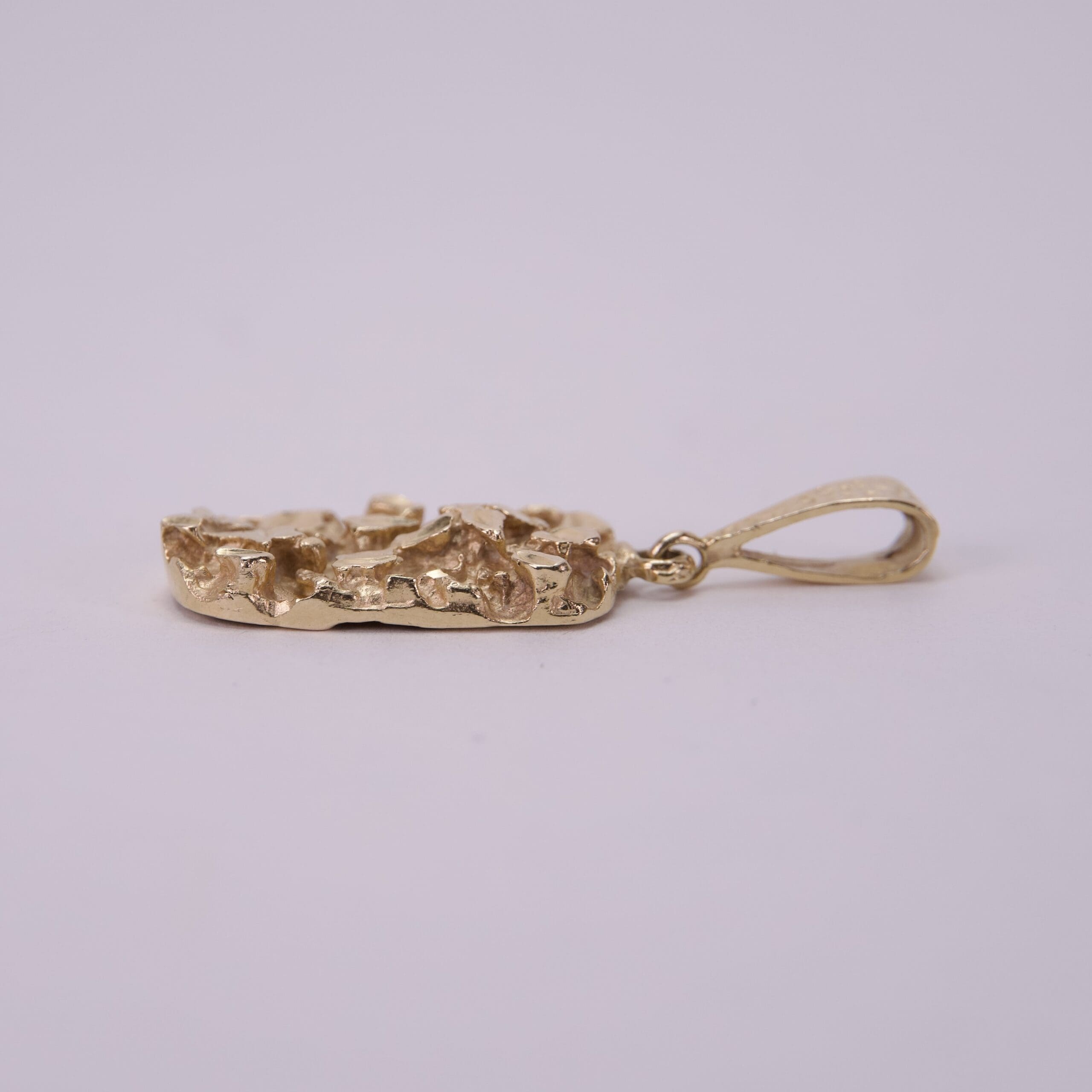 Gold pendant with textured design, side view.
